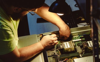 man-repairing-a-computer-server-under-a-lamp-.jpg Man repairing a computer server under a lamp.