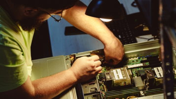man-repairing-a-computer-server-under-a-lamp-.jpg Man repairing a computer server under a lamp.